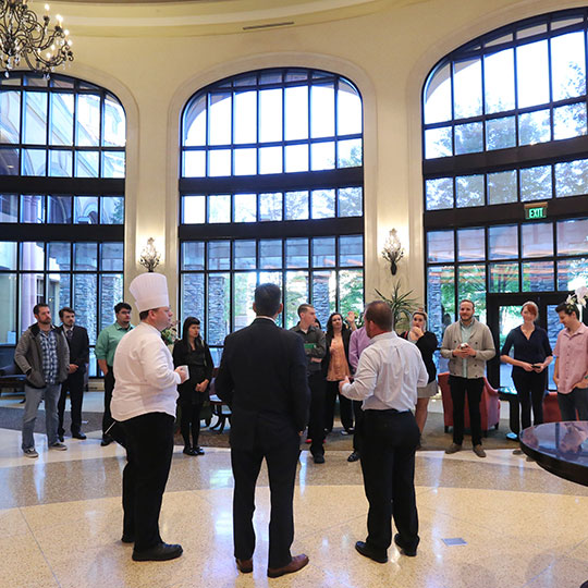 Students exploring large hotel lobby while listening to a chef speaking