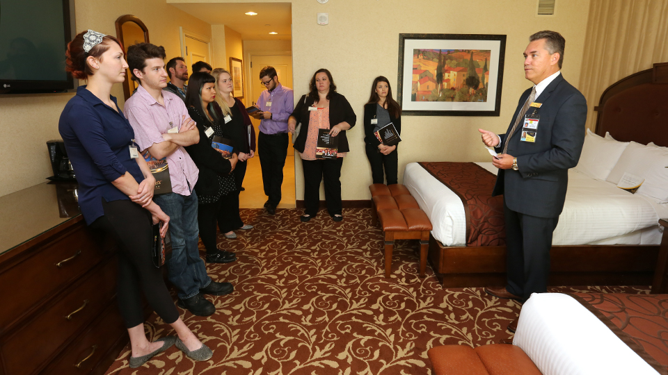 Students listen to a presentation given in a hotel room