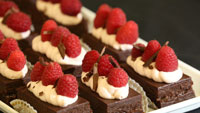 Plate of small chocolate cakes with whipped cream and raspberries