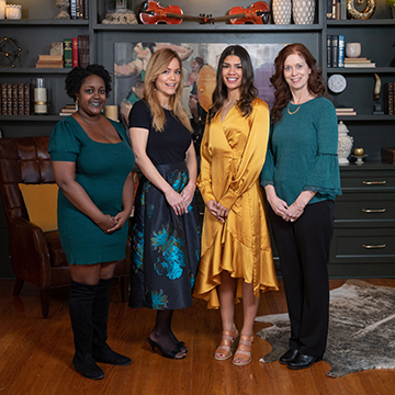 Four interior design students posing in front of a bookcase