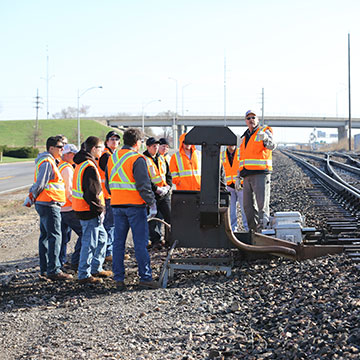 NARS students gather for an outdoor lesson along train tracks.