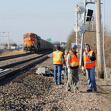 A BNSF locomotive pulls a train in a students watch from along the tracks.