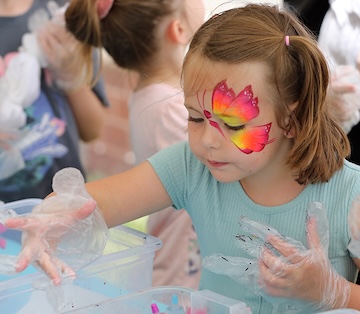 Young girls with butterfly tattoos on their faces.