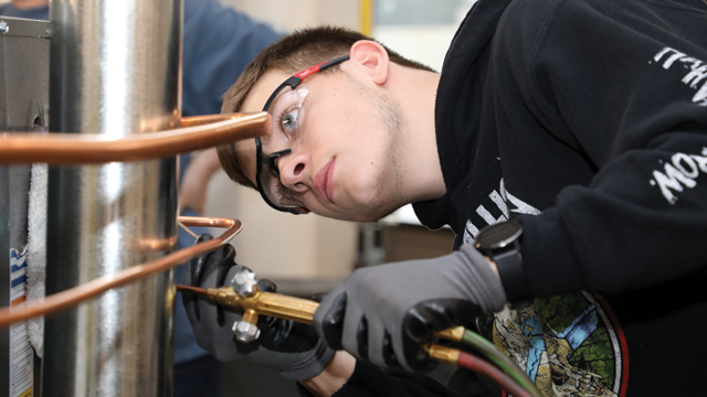 Student looking at a pipe in the H V A C lab