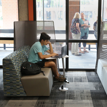 A student studies his computer at a bench in the CoLab.