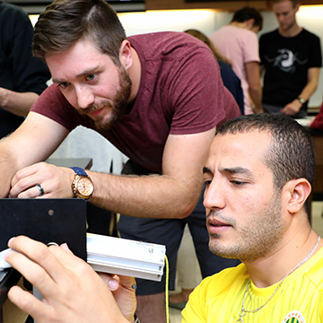 Two male students adjust the connections on an electrical project.