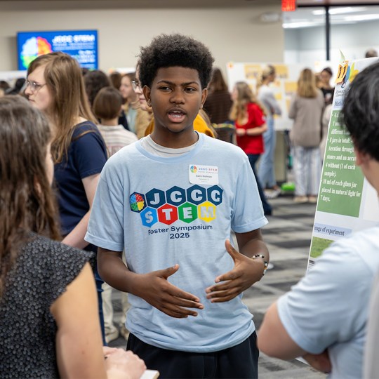 Student explaining his project at the STEM Poster Symposium