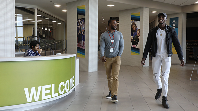 a JCCC staff member walks with a student in the Student Center near the Welcome desk