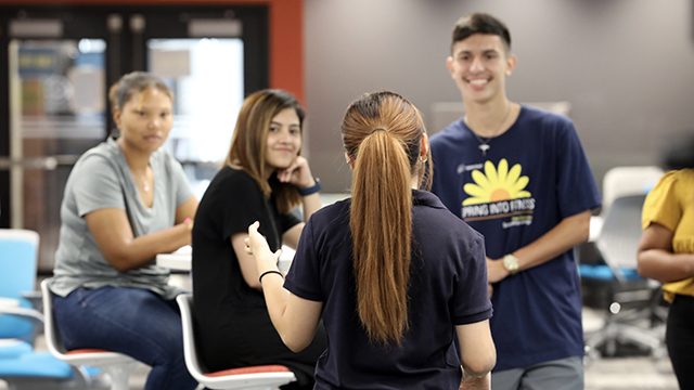 An admissions rep talks to a group of prospective students in the student engagement center