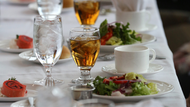 Close-up of a luncheon table set with salad, iced tea and water by our catering department