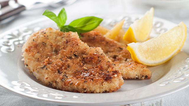 Breaded fish filet garnished with lemon wedges