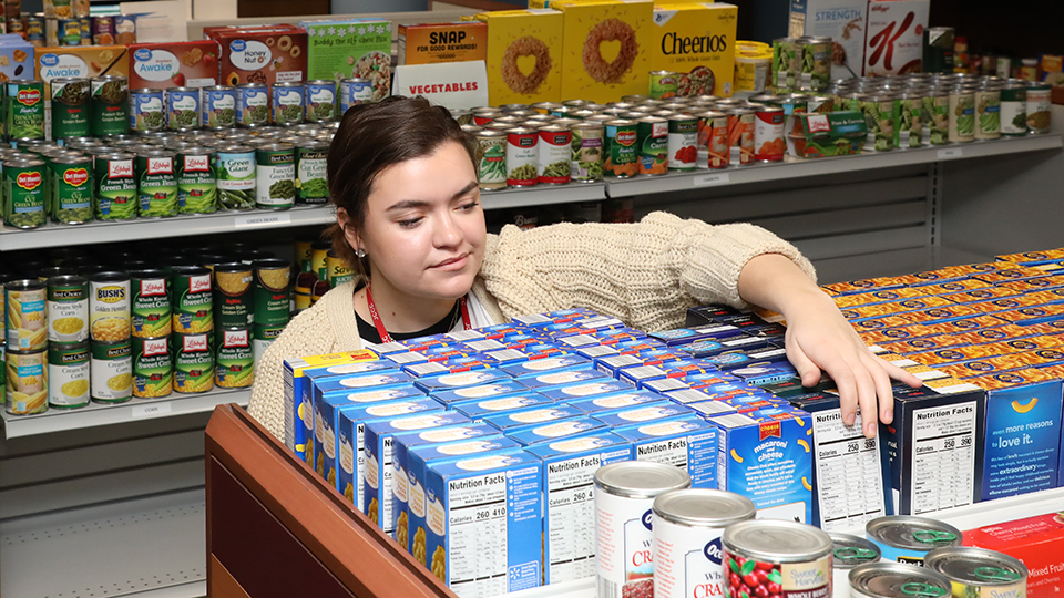 Student volunteer stocking shelves in the Basic Needs Center