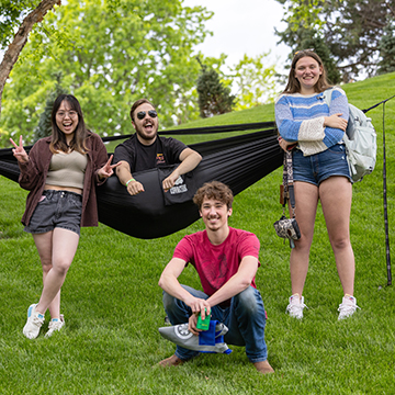 Students posing on Haun Hill, one sitting in a hammock