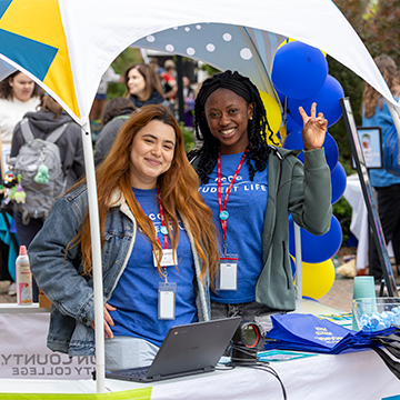 Student Activities staff standing in a tent as they welcome students to the Cav Craze celebration