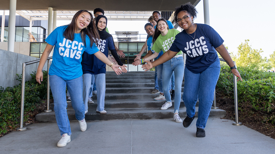 Students on steps with welcome arms.