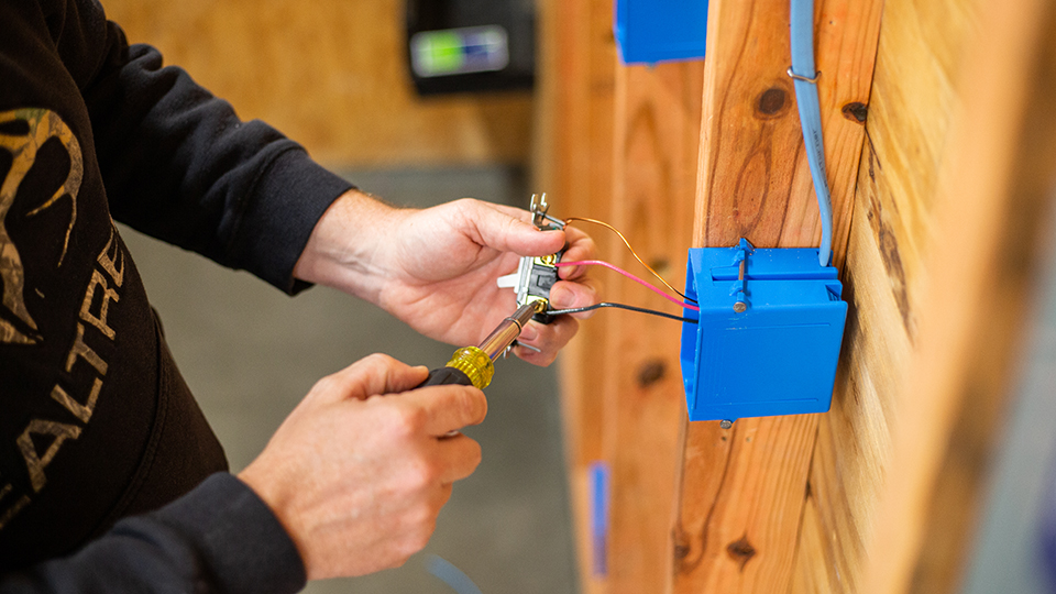 closeup of hands working on wiring for a light switch