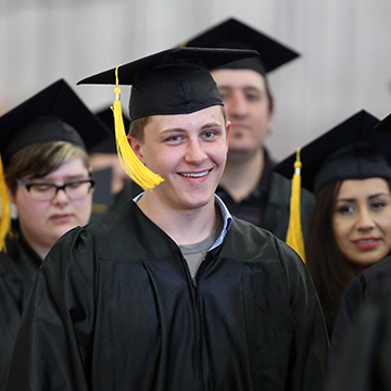 Man wearing cap and gown at GED graduation ceremony.