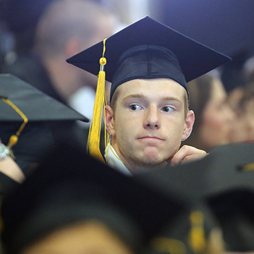 Man sitting among graduates at GED graduation ceremony.