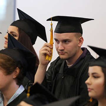 Man changing tassel at GED graduation ceremony.