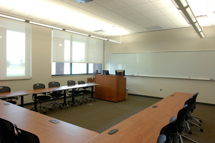 A meeting room set up with tables and chairs in a U shape.