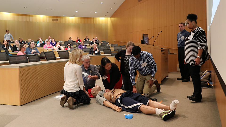 conference attendees participate in a demonstration involving a simulation dummy