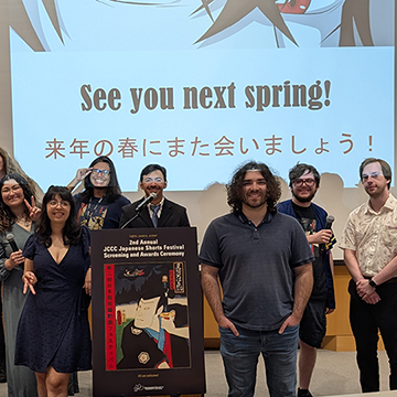 a group of festival participants pose for a picture in front of a screen that says "see you next spring!"