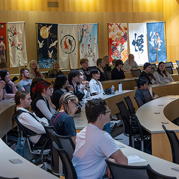 a wide angle shot of the festival in the Hudson Auditorium. The auditorium is decorated with colorful banners depicting Japanese artwork.