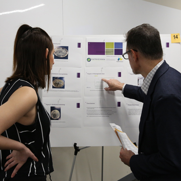 A professor and student look over a poster at the Science and Math Poster Symposium.