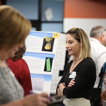 A student hosts a poster presentation at the Science and Math Poster Symposium.