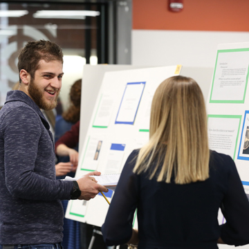 Two students look over posters at the Science and Math Poster Symposium.