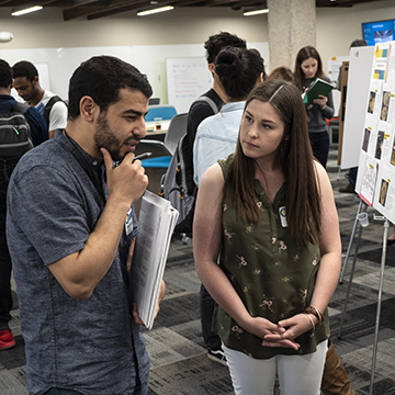 Two attendees analyze a symposium poster.