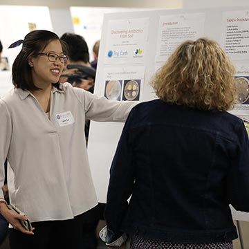 Student shows her work to faculty at the symposium.