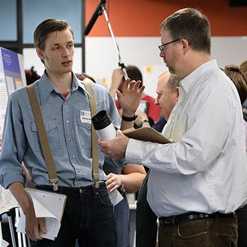 A student talks to a member of the faculty at the 2019 symposium.
