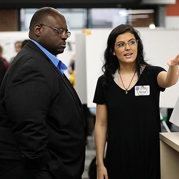 A student shares her findings with a member of the faculty at the 2019 symposium.