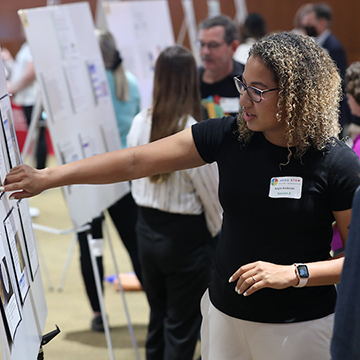 A student points to information displayed on a research poster