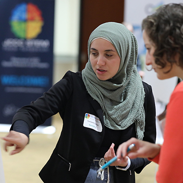 A student in a head scarf explains her research project