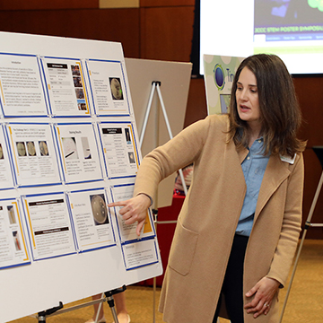 Two students review research displayed at the STEM Poster Symposium