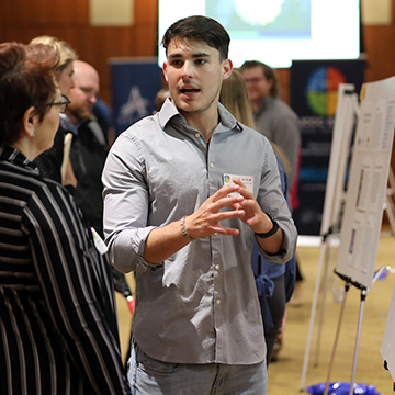 A male student explains his research during the STEM Poster Symposium at JCCC