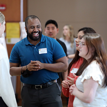 A smiling JCCC student explains his research to STEM Poster symposium attendees