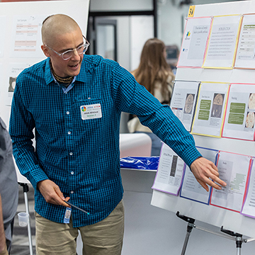 a student points to his poster while explaining a concept