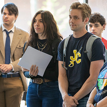 a group of five student listen intently to a speaker while waiting to enter the CoLab