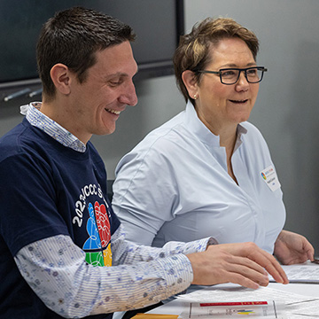 two smiling event organizers sit a at table while organizing papers