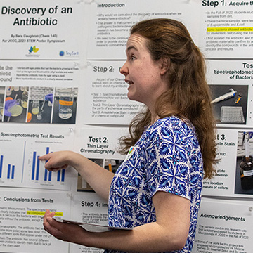 a female student explains something about her poster to a male symposium guest
