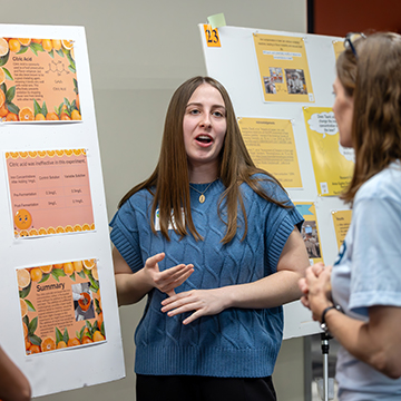 a student explains her research at the JCCC STEM Poster Symposium