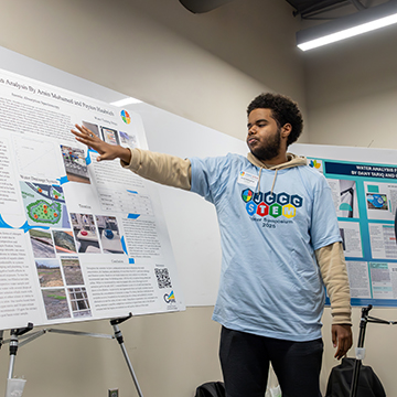 a presenter points to information on his poster at the JCCC STEM Poster Symposium