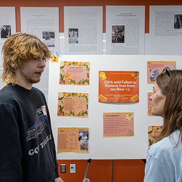 a faculty member talks to a student about their poster