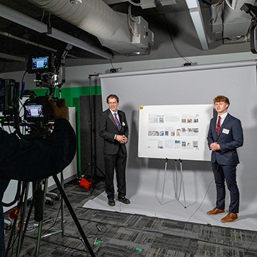 two jccc student pose for a professional photo next to their poster at the STEM Poster Symposium