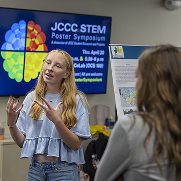 a student explaining her research to a group of listeners