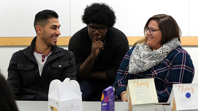 Three students converse at a table.