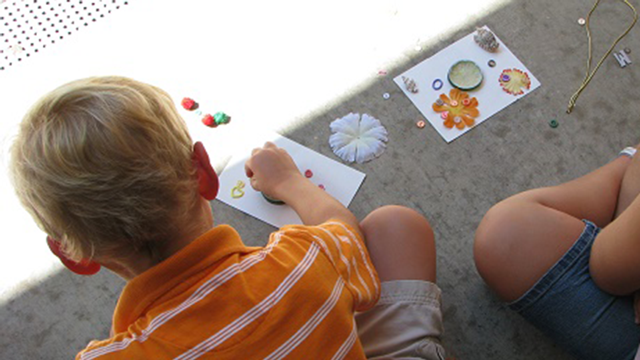 Children work on a craft project with flowers.